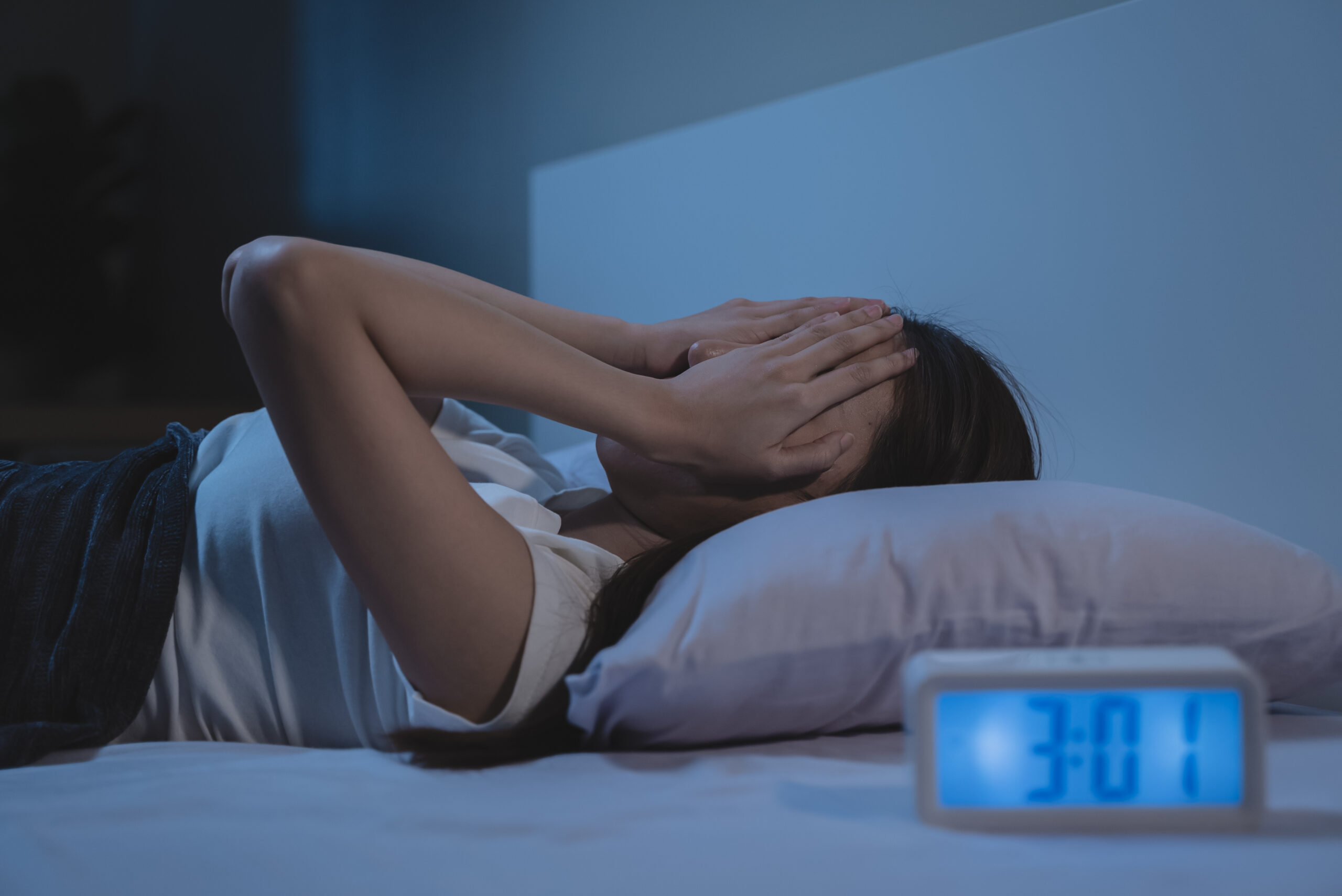 woman have insomnia on the bed selective focus on alarm clock at three in the morning.